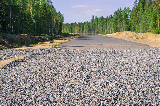Construction of a new highway in the forest.  Asphalt paving on gravel and sand