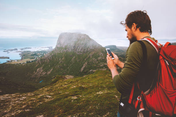 istock Man backpacker using smartphone navigation hiking in mountains travel blogger influencer lifestyle summer trail outdoor vacation in Norway Vesteralen islands 1333018836