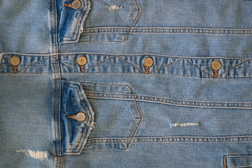 a large part of a buttoned blue and worn denim jacket close-up