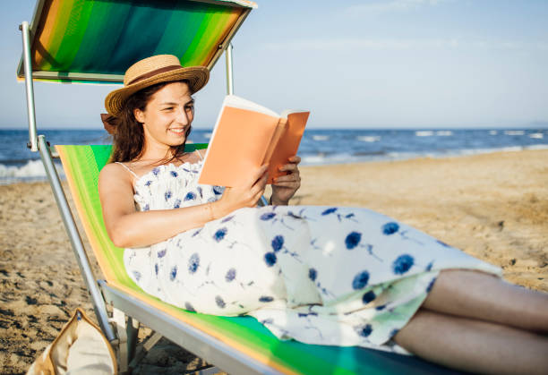 istock Female reading and enjoying sunset on beach by the ocean 1333020649