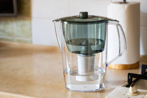 istock Water filter jug on kitchen table. Clean water concept. Filtration water 1333025557