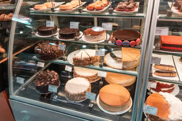 Photo of A variety of cakes on the window of a pastry shop with price tags. Simple carbs and a treat concept