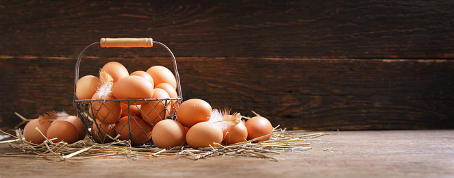 basket of fresh chicken eggs on a wooden background