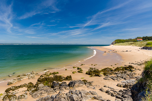 A large sandy beach and shallow sea on Caldey Island, Wales, UK