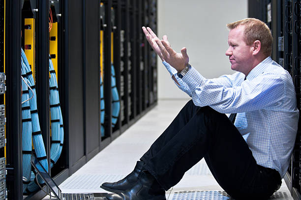 Frustrated businessman staring at row of servers stock photo
