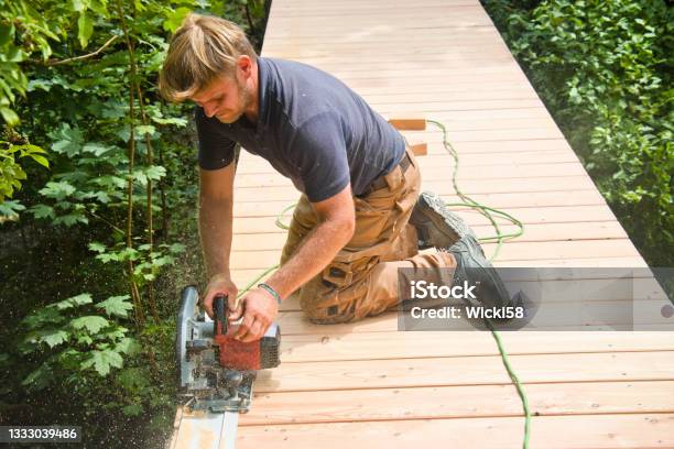 Carpenter Straighten Edges Of Boards On A New Boardwalk Stock Photo - Download Image Now