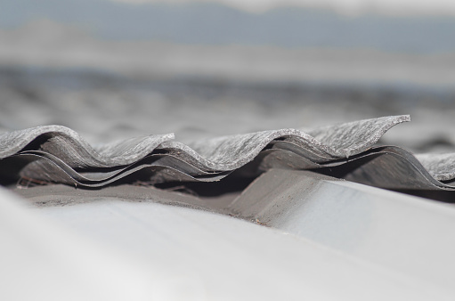 selective focus of the wavy side edges of the building roof. gray, old and shabby asbestos top cover texture