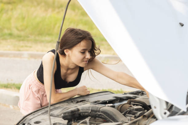 engine problems,woman with a broken auto on the road is upset with an open hood, waiting for help