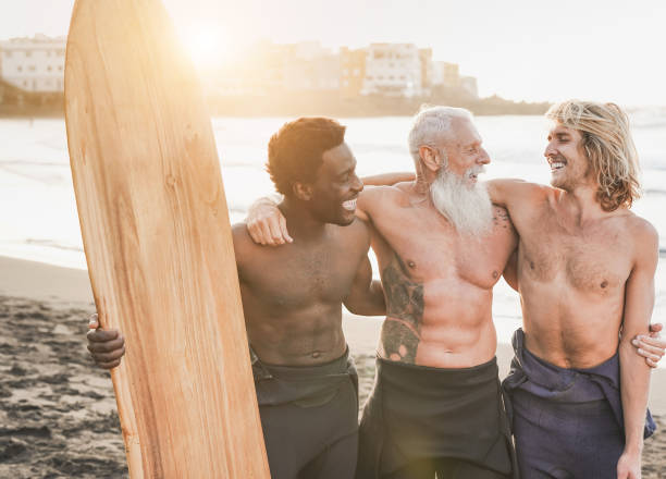 istock Happy multiracial surfer men smiling in camera on the beach at sunset - Multi generational people and extreme sport concept 1333049516