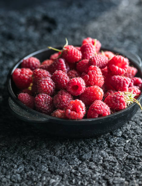 istock Raspberries in a clay bowl on a dark wooden table, selective focus. 1333051314