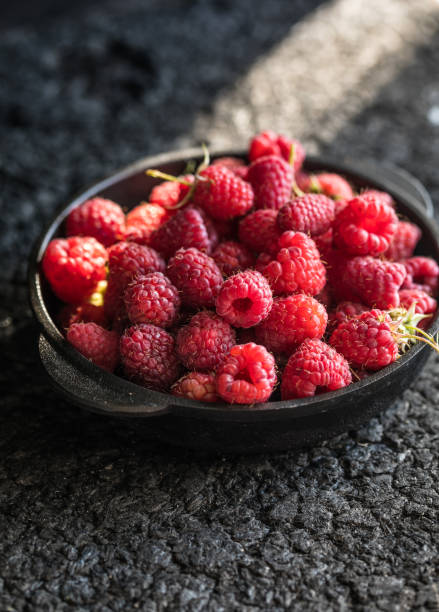 istock Raspberries in a clay bowl on a dark wooden table, selective focus. 1333051362
