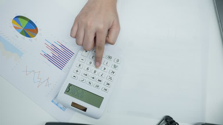 slow motion top view scene of accountant man using calculating on calculator to summarize or consider on statistic report at office for business and financial concept