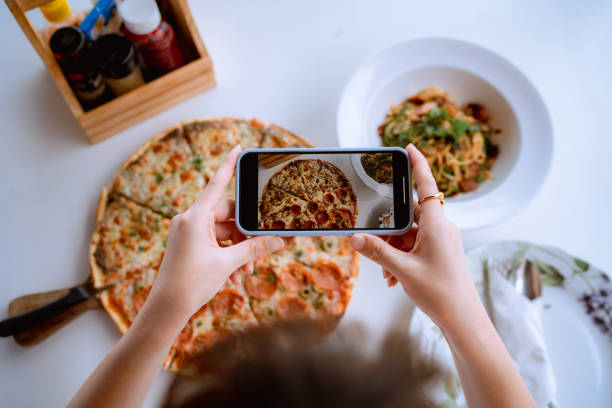 istock Woman using smart phone photographing pizza at restaurant. 1333061269