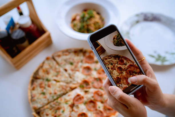 istock Woman using smart phone photographing pizza at restaurant. 1333061277