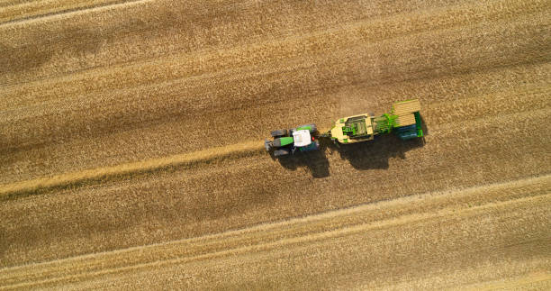 Straw balers from drone point of view Directly above tractor with straw baler. Summer and harvest time. Farmer  saving straw for animals and energy. hay baler stock pictures, royalty-free photos & images