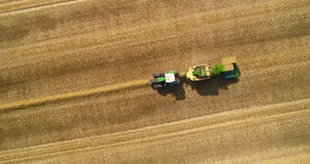 Directly above tractor with straw baler. Summer and harvest time. Farmer  saving straw for animals and energy.