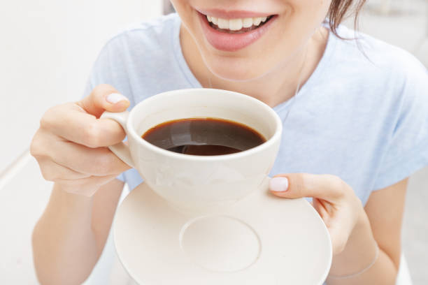 Happy woman drinks a black espresso coffee and smiles. The concept of problems with the color of teeth from bad habits Happy woman drinks a black espresso coffee and smiles. The concept of problems with the color of teeth from bad habits Coffee stock pictures, royalty-free photos & images