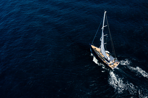 View from above, stunning aerial view of a sailboat sailing on a blue water at sunset. Sardinia, Sardinia, Italy.