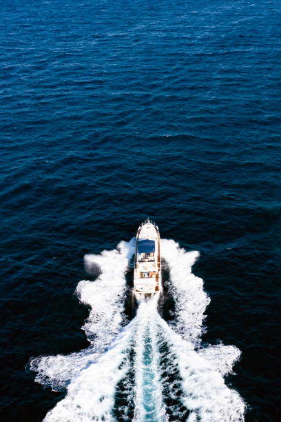 вид сверху, потрясающий вид с воздуха на роскошную яхту, курсировающую по голубой воде, создающую след. коста смеральда, сардиния, италия. - motorboating travel vacations transportation стоковые фото и изображения