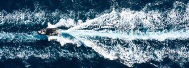 vista dall'alto, splendida vista aerea di una barca che naviga su un'acqua blu creando una scia. costa smeralda, sardegna, italia. - recreational boat motorboat speedboat aerial view foto e immagini stock