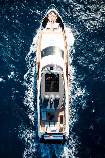 View from above, stunning aerial view of a luxury yacht cruising on a blue water creating a wake. Costa Smeralda, Sardinia, Italy. stock photo