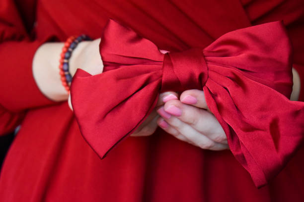 istock Human hand holding a red satin bow 1333074937