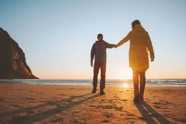 Photo of Romantic couple in love holding hands walking on beach man and woman traveling together lifestyle vacation trip outdoor