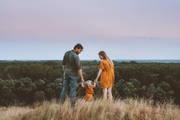 genitori di famiglia madre e padre con bambino che si tiene per mano camminando all'aperto insieme uno stile di vita sano paesaggio rurale della foresta naturale - baby first steps autumn child foto e immagini stock