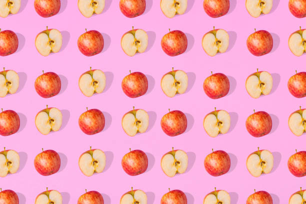 istock Outstanding pattern of fresh whole apples  and apple halves on a pink  background. 1333078737