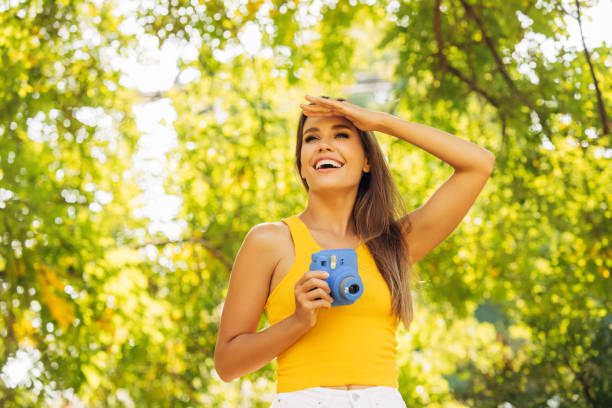 Happy beautiful woman with analog camera in the park