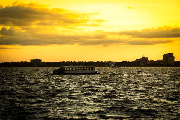 The silhouette of a water taxi is outlined just beneath the sunlit horizon near dusk on Jacksonville, Florida's St. Johns River.