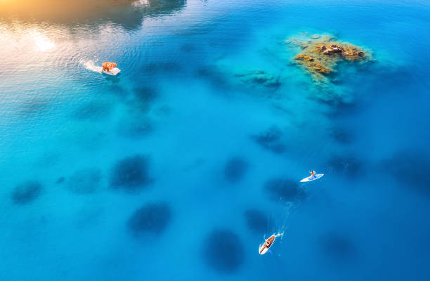 Aerial view of people on floating sup boards on blue sea, boat, rock, stones at sunset in summer in Oludeniz, Turkey. Tropical landscape. Kayaks on clear water. Active travel. Top view of canoe. Sport Aerial view of people on floating sup boards on blue sea, boat, rock, stones at sunset in summer in Oludeniz, Turkey. Tropical landscape. Kayaks on clear water. Active travel. Top view of canoe. Sport kayak surfing stock pictures, royalty-free photos & images