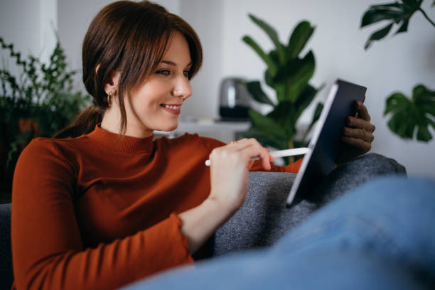 istock Cheerful Young Woman Using Digital Tablet at Home 1333092800