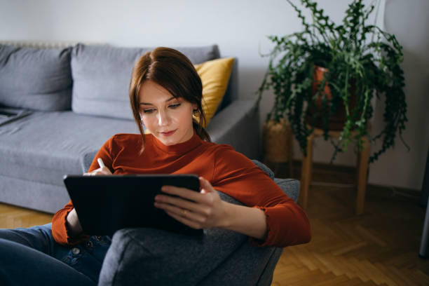 istock Beautiful Young Woman Using Digital Tablet at Home 1333092802