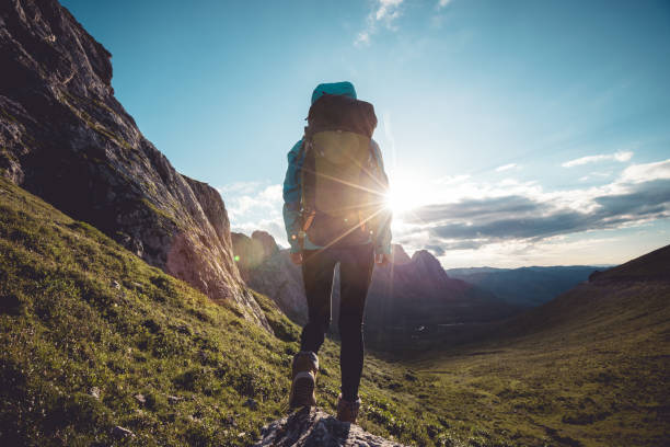 istock Successful woman backpacker hiking on sunset alpine mountain top 1333095502