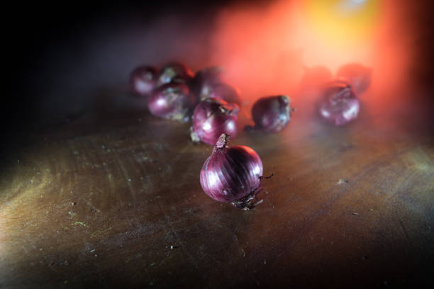 Vegetable concept. Purple onions on wood in dark. Selective focus. Colorful background.