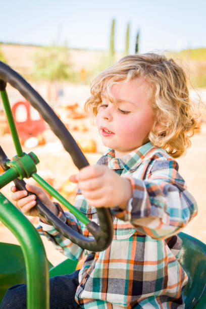istock Little Boy Having Fun In A Tractor in a Rustic Ranch Setting at the Pumpkin Patch. 1333096484