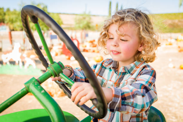 istock Little Boy Having Fun In A Tractor in a Rustic Ranch Setting at the Pumpkin Patch. 1333096487
