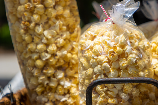 Plastic sleeves filled with tasty buttered popcorn snacks wait for sale at a summer county fair.