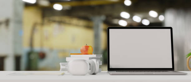 istock Laptop empty screen mockup, headphone, books, apple on top table, white copy space 1333117989