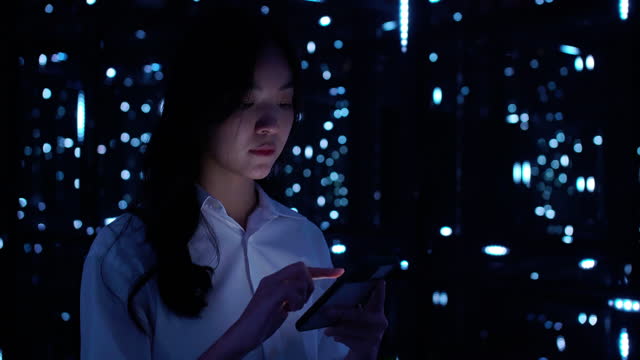 Asian teenage girl using mobile smart phone with a 5G while looking in colourful UV lighting at dark night.Mobile Internet, New generation networks.Visualizing 5G concept.