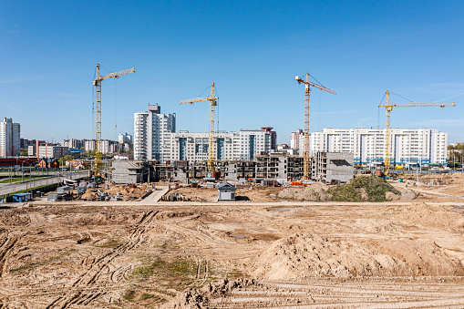 construction of a modern residential complex. cranes and buildings construction site against blue sky. drone photo.