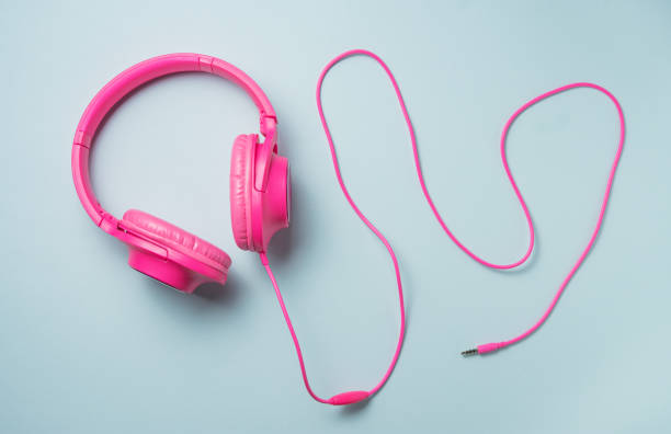istock pink large headphones with a wire on a blue background. Top view 1333124132