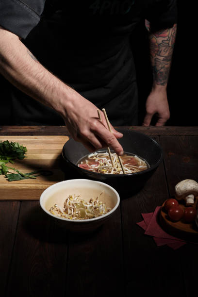 istock Chef adding white bean sprouts with chopsticks to pho bo 1333133469