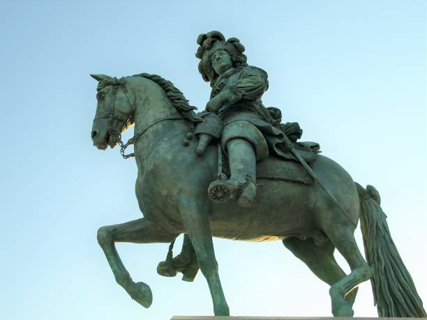 Equestrian Statue of King Louis XIV of France outside the gates of Versailles on a sunny day in Autumn. The statue was cast in bronze in 1881 by the artist, Charles Crozatier. It is located in the Place d' Armes. The sky takes on a lighter colour of blue as the background gets closer to the setting sun, when compared to other images in the series.