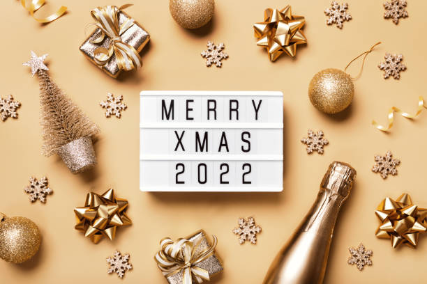 lightbox with text merry xmas 2022 and golden christmas decor on beige background. creative layout in neutral monochrome colors - 3666 imagens e fotografias de stock