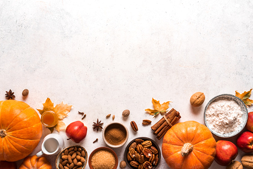 Autumnal fall baking background with apples, pumpking, nuts and seasonal spices for cooking apple or pumpking pie. Thanksgiving and cozy autumn holidays concept.