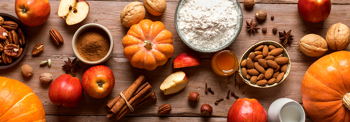 Autumnal fall baking background with apples, pumpking, nuts and seasonal spices for cooking apple or pumpking pie. Thanksgiving and cozy autumn holidays concept.