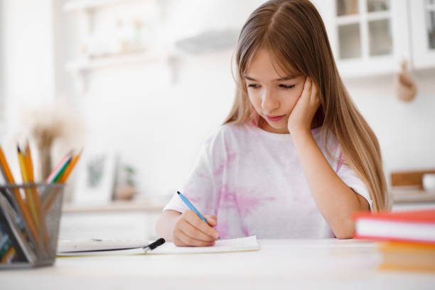 istock Teenage girl making notes in notepad, doing homework at table at home 1333138464
