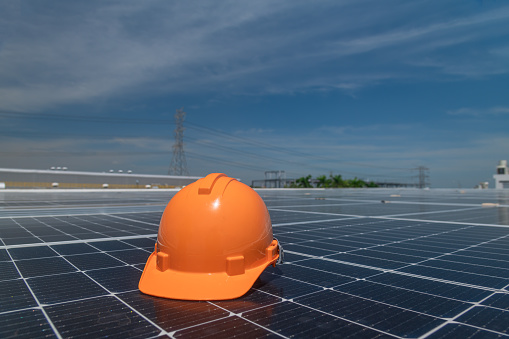 Helmet of worker putting on solar cell panel in industry roof field ecology  alternative power concept.